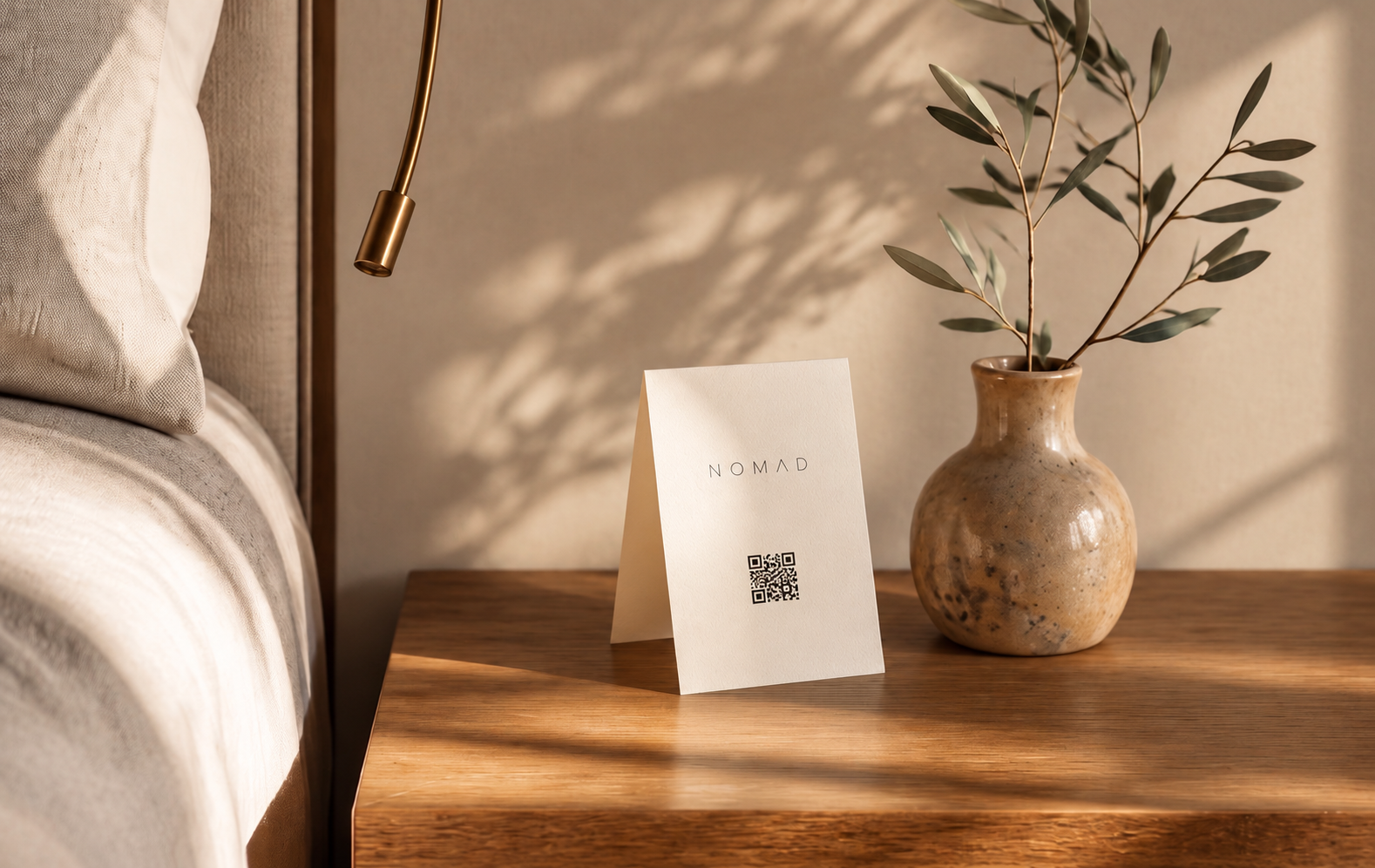 A minimal hotel bedside table with a small printed card carrying a QR code